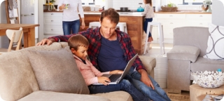 Father helps son use a laptop.